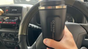 運転席でタンブラーを手に取る様子。車内でも使いやすいサイズ感